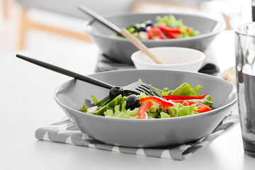 Plates with fresh Greek salad and glass of beverage on table in restaurant