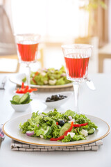 Plates with fresh Greek salad and glasses of wine on table in restaurant