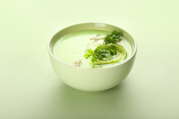 Bowl with green gazpacho on color background