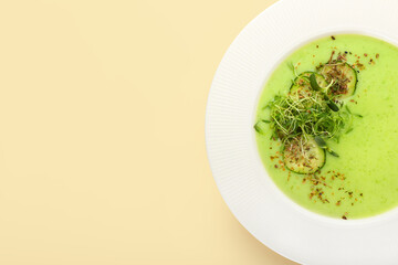 Plate with green gazpacho on color background