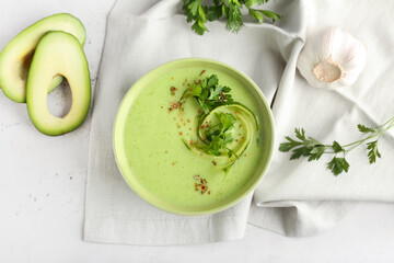 Bowl with green gazpacho and ingredients on light background