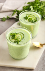 Glasses with green gazpacho on grey background