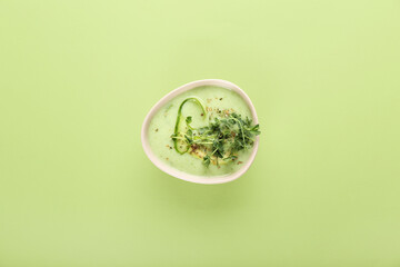Bowl with green gazpacho on color background