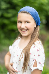 Porträt eines jungen, hübschen, nachdenklich Mädchens mit blauem Kopftuch im Wald. Lebensfreude, Glück, Gesundheit, Freiheit sind Motivation in der grünen, blühenden Natur.