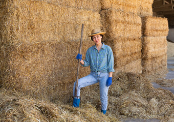 Smiling asian woman farmer in strow hat resting on hayloft at cow farm