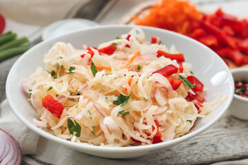 Plate with tasty sauerkraut on light wooden background