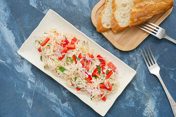 Plate with tasty sauerkraut and fresh bread on color background