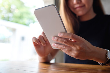 Closeup image of a beautiful young asian woman holding and using mobile phone