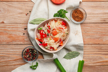 Bowl with tasty sauerkraut and ingredients on wooden background
