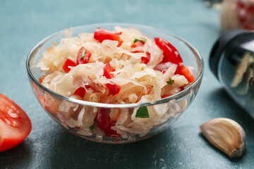 Bowl with tasty sauerkraut on color background