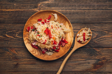 Plate and spoon with tasty sauerkraut on wooden background