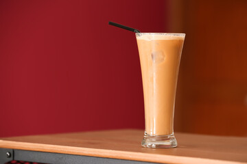 Glass of tasty iced coffee with milk on table
