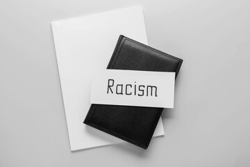 Paper piece with word RACISM and books on white background