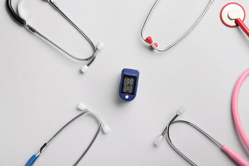 Pulse oximeter and stethoscopes on light background