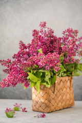 Bouquet of colorful lilac flowers in a wicker basket. Spring summer concept. Floral, interior, nature