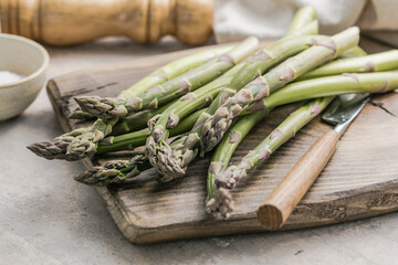 Asparagus cooking concept, top down view on a cutting board with fresh bunch of asparagus, spring healthy cooking idea