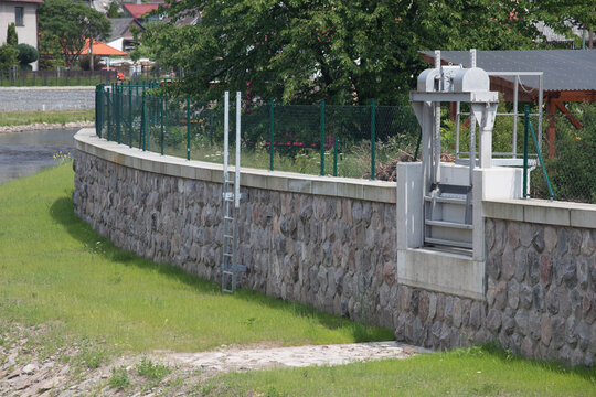 Modern flood protection wall in the style of the historic city wall. Permanent measures against floods. Dikes, gate valves, gates and walls. 
Flood gates protecting city against flooding from stream.