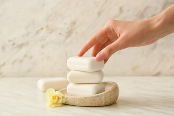 Female hand with soap bars on light background