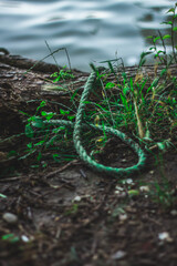 the green cut rope lies on the ground near the water 