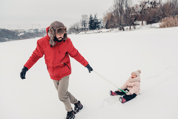Fototapeta na wymiar Handsome bearded young dad and his little cute daughter are having fun outdoor in winter. Enjoying spending time together. Family concept