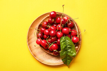 Bowl with tasty ripe cherry on color background