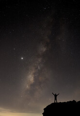 Milky Way. Night sky with stars and silhouette of a standing happy man with yellow light. Space background