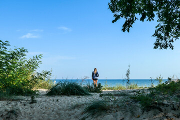 A woman in shorts standing at a confluence of a small river to the Baltic Sea in Poland. There are...