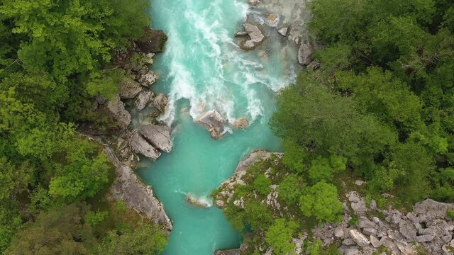 Aerial - Emerald river with huge rocks flowing through the spring forest
