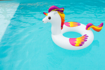 inflatable float in the shape of a colorful unicorn in the pool © pedro