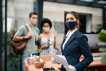 Female hotel receptionist wearing face mask while working during coronavirus pandemic.
