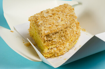 The cake is packaged in a white paper box on a light blue backgr