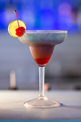 Blue and Red Cocktail with Cherry and Lemon Slice with Blue Blurred Background