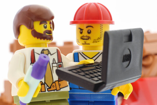 Lego minifigure of builder and engineer with laptop closed up editorial illustrative image
