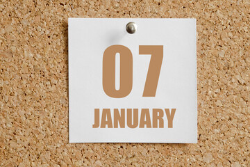 january 07. 07th day of the month, calendar date.White calendar sheet attached to brown cork board.Winter month, day of the year concept