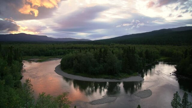 Clouds over a bend in a river in a green, mountain wilderness.
