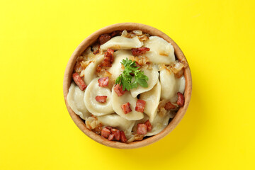 Bowl of vareniki or pierogi on yellow background