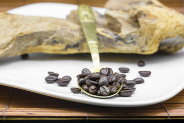 Coffee beans with a wooden coffee bean grinder in the background on a wooden surface with metal filter and drift wood with copyspace