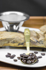 Coffee beans with a wooden coffee bean grinder in the background on a wooden surface with metal filter and drift wood with copyspace