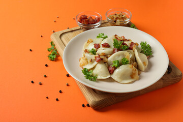 Concept of tasty food with vareniki or pierogi on orange background