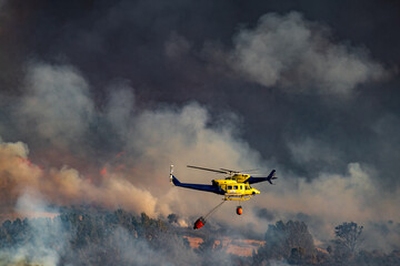 Two helicopters with bambi bucket team working on fire extinction