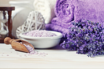 Lavender flowers, aromatic sea salt and towels. Concept for spa, beauty and health salon, cosmetics store. Close up photo on white wooden background.
