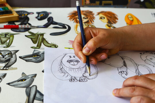 The animator draws with a pencil and draws characters from cartoons, comics or puppet shows. Mowgli's play. Preparing to make a doll. The designer creates sketches. Comics, cartoons, puppet theater
