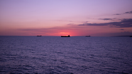 Naklejka premium Sunset in the sea with view of tanker vessel on the horizon line