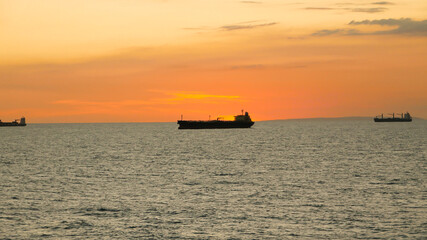 Sunset in the sea with view of tanker vessel on the horizon line