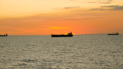Obraz premium Sunset in the sea with view of tanker vessel on the horizon line
