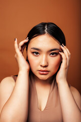 Fototapeta premium young pretty asian woman cheerful smiling posing on warm brown background, lifestyle people concept