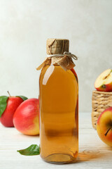 Homemade apple vinegar and ingredients on white wooden table