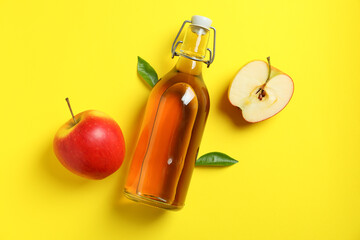 Homemade apple vinegar and ingredients on yellow background