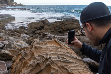 Young Man Taking a Picture whit Phone to a Sea Landscape on a Summer Day. Travel Concept