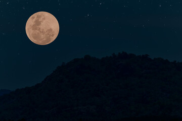 Fototapeta na wymiar Full moon on the sky with mountain silhouette.
